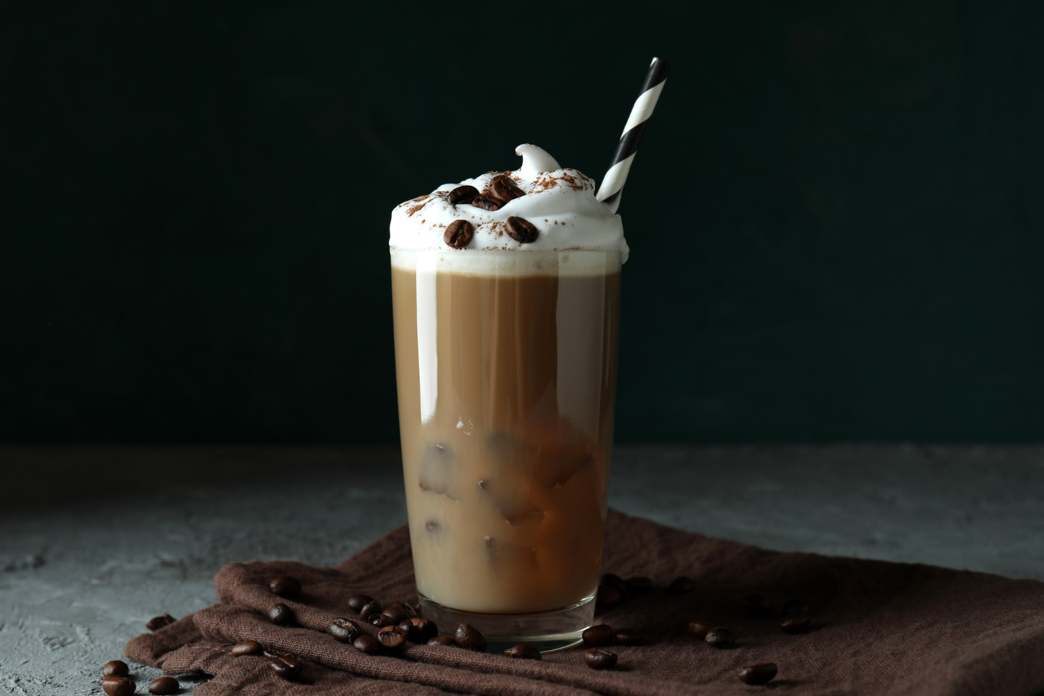 Καλοκαιρινός, κρύος καφές τύπου freddoccino, με σαντιγί στην κορυφή και χοντρό, ασπρόμαυρο καλαμάκι.